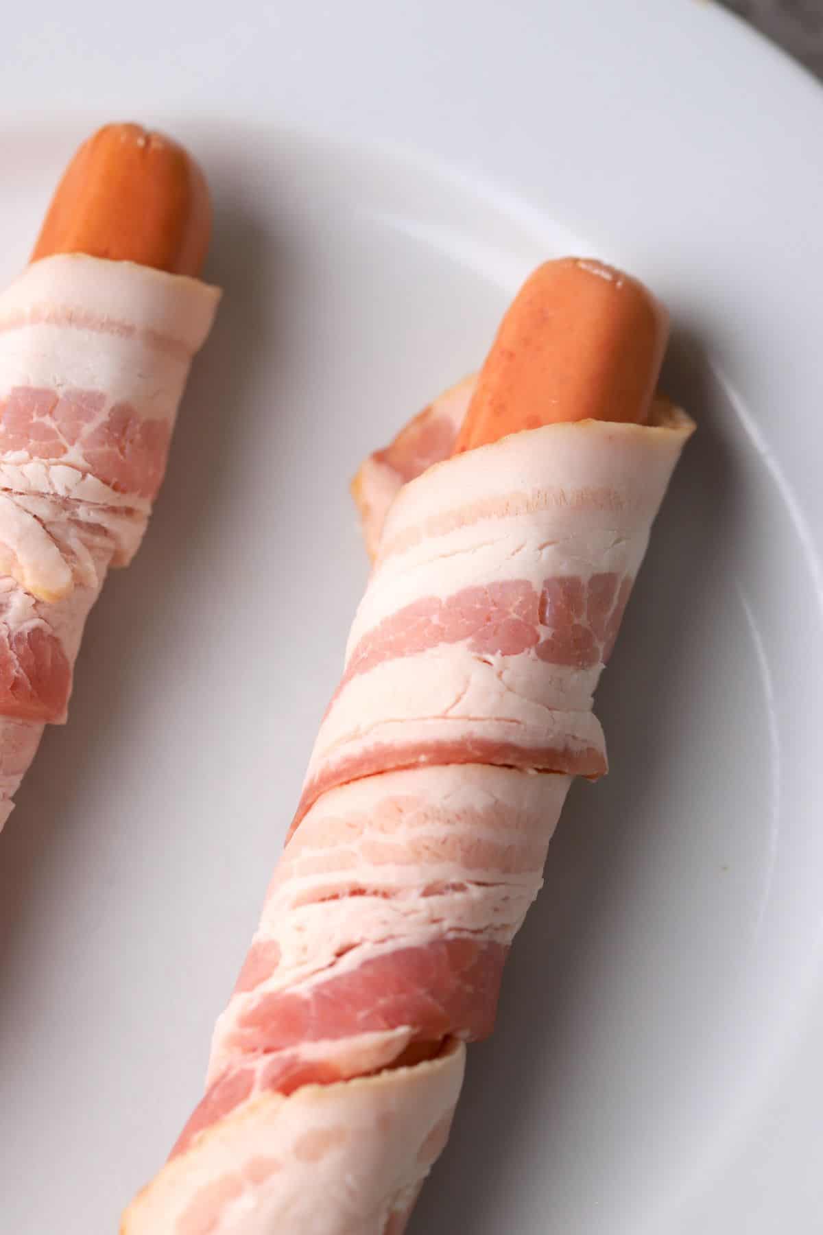 two uncooked bacon wrapped hot dogs.