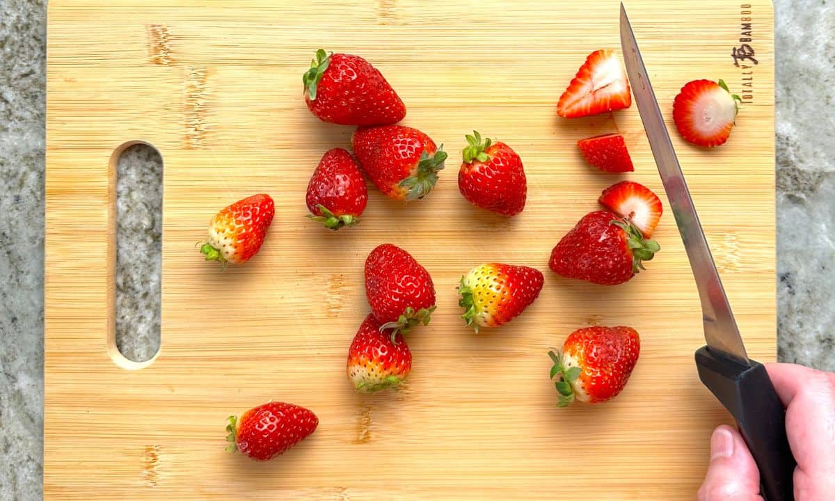 cutting the strawberries into quarters.