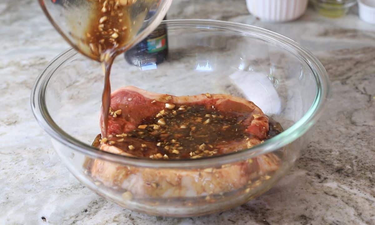 pouring the marinade over the steaks in a bowl.