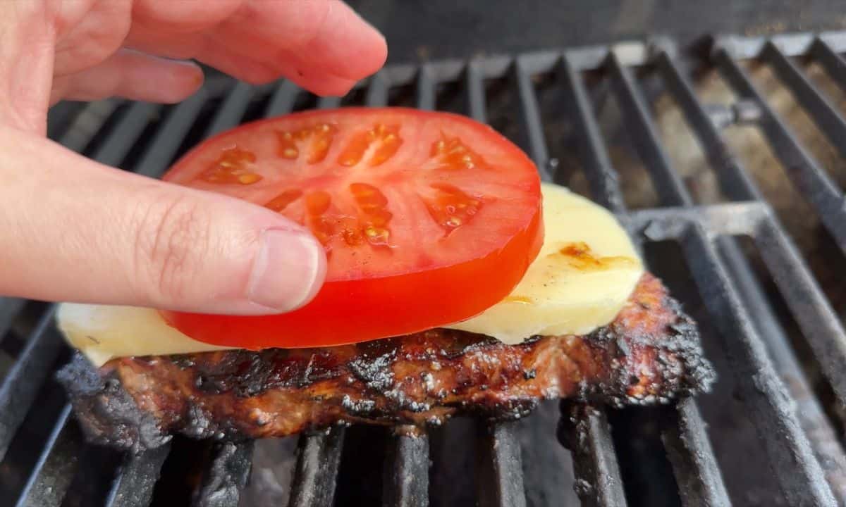 topping the steak and mozzarella with a tomato.