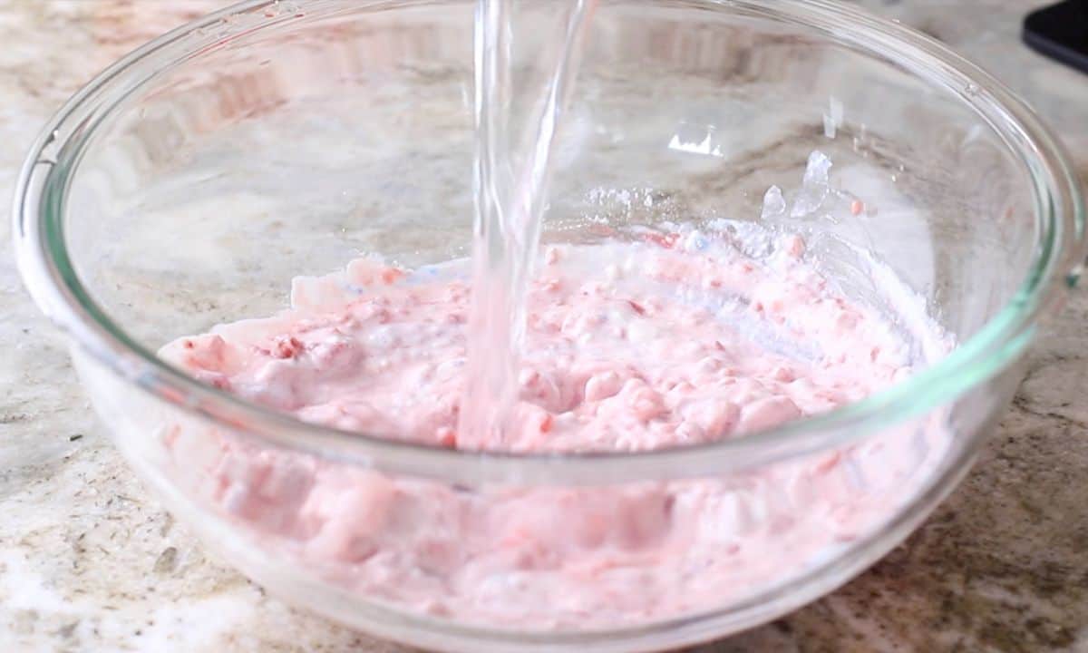 pouring water into the raspberry mixture.