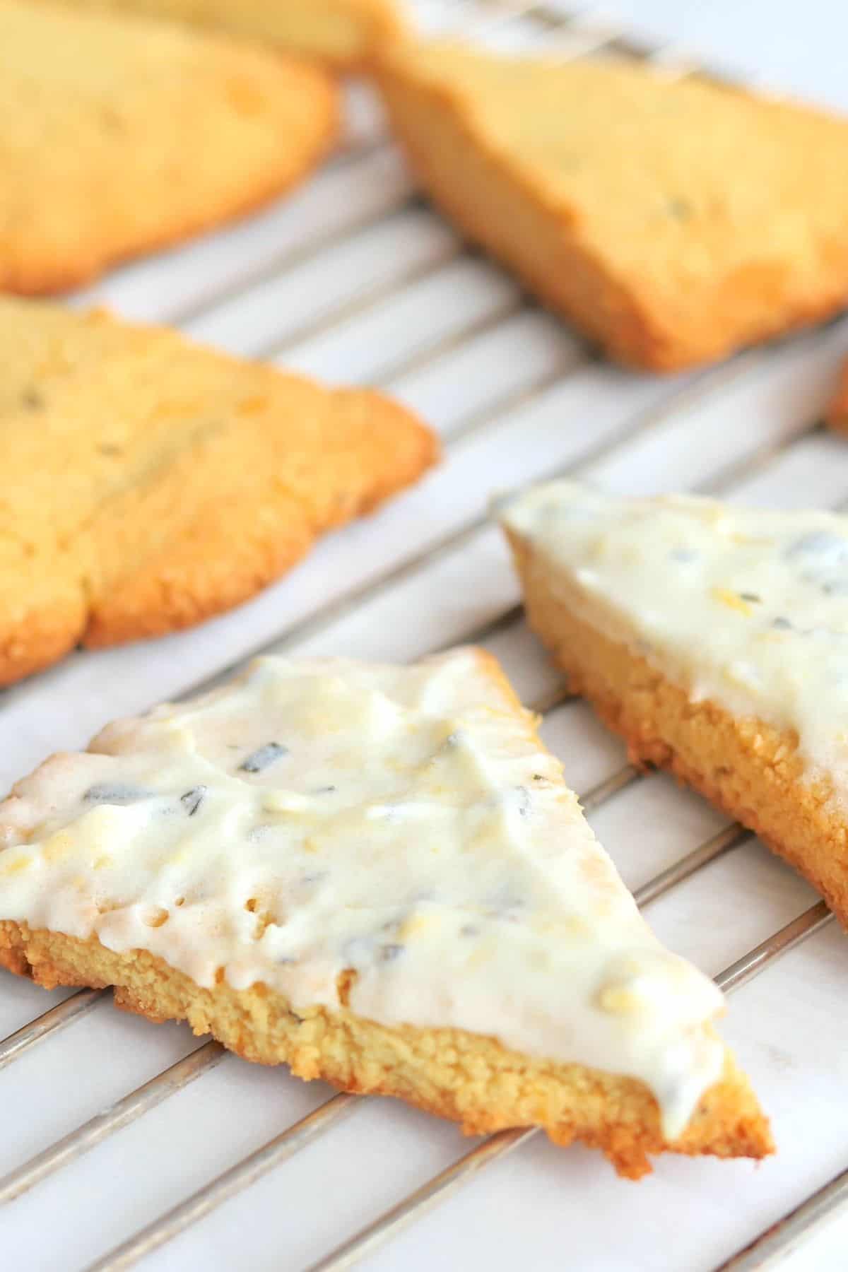 Almond flour scones on a cooling rack with a lemon rosemary frosting.