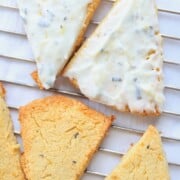 Almond flour scones on a cooling rack with a lemon rosemary frosting.