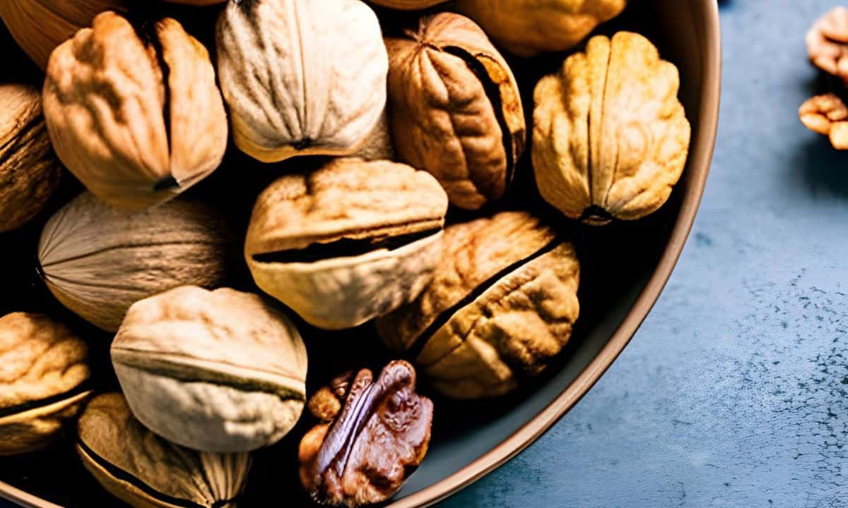 walnuts with and without shell in a brown bowl.