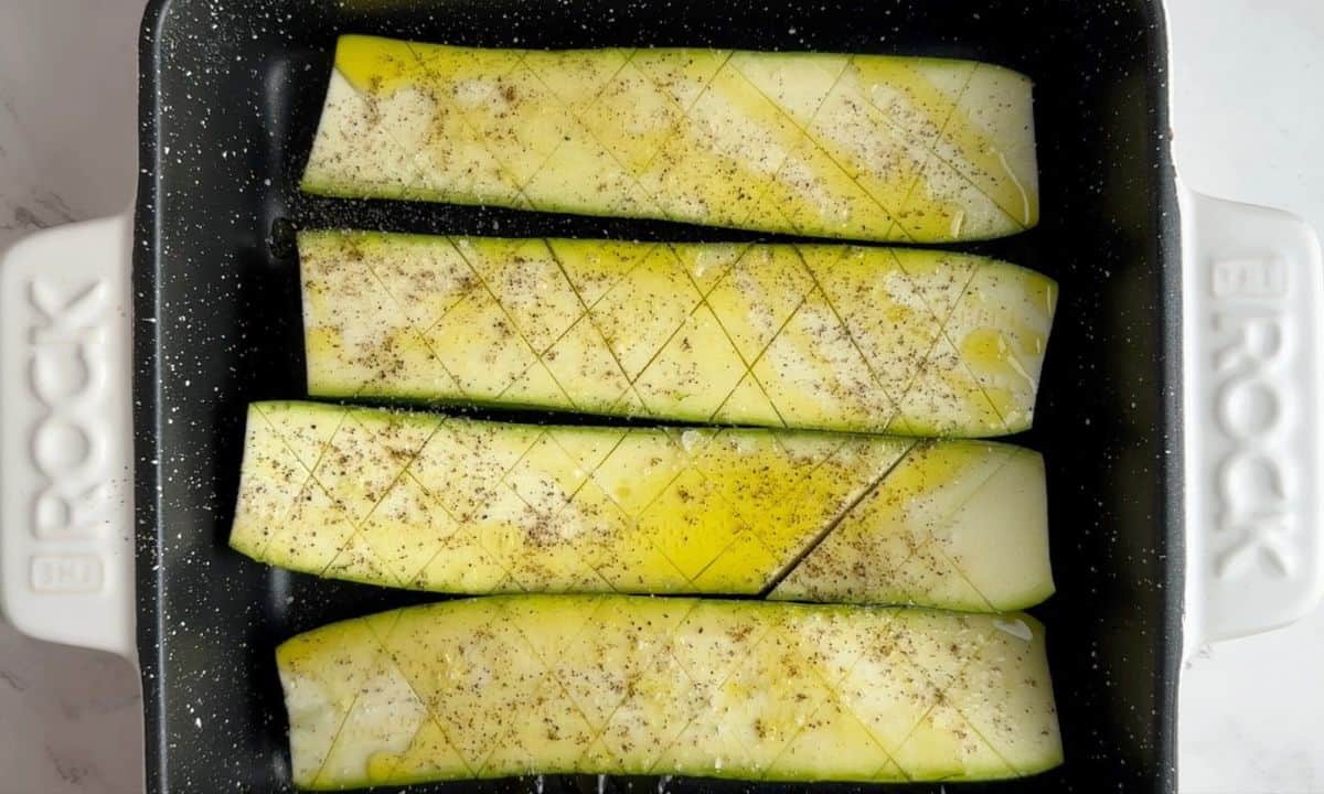 raw zucchini halves in the pan topped with olive oil, salt and pepper.