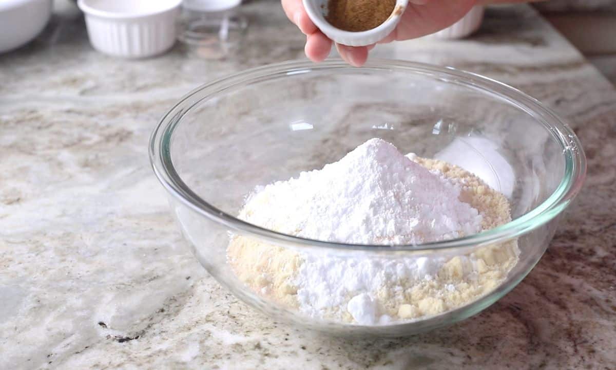 adding dry ingredients into a large glass bowl.