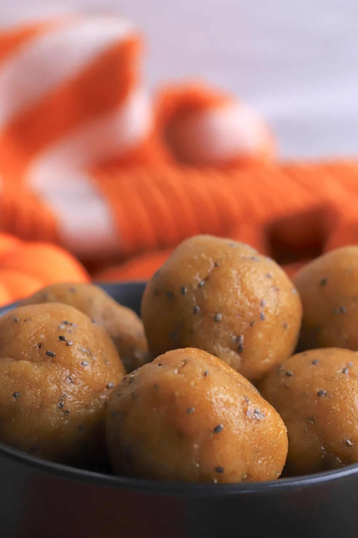 Closeup of the pumpkin protein balls in the ball with an orange kitchen towel in the background.