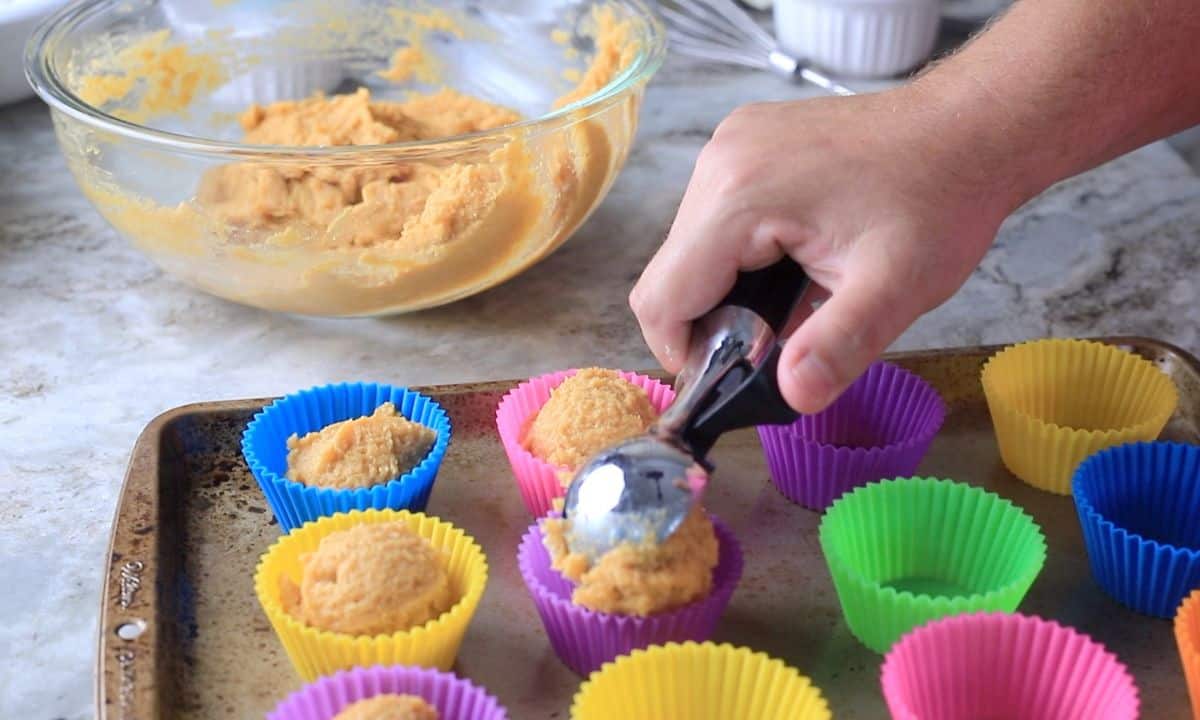 scooping muffin batter into silicone molds.