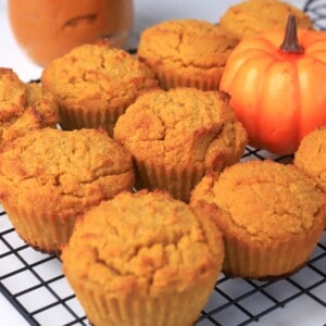 pumpkin muffins on a cooling rack with a small pumpkin.