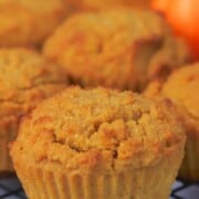 pumpkin muffins on a cooling rack with a small pumpkin.
