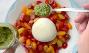 A spoon with basil pesto over the salad.