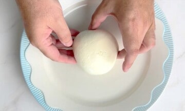 Placing the burrata on a white dish with a blue rim.