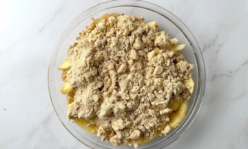 Uncooked apple crisp in a glass pie plate.
