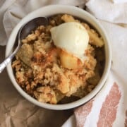 A bowl of sugar free apple crisp topped with a scoop of vanilla ice cream.