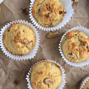 sugar free banana muffins on a brown parchment paper with scattered walnut piecces.