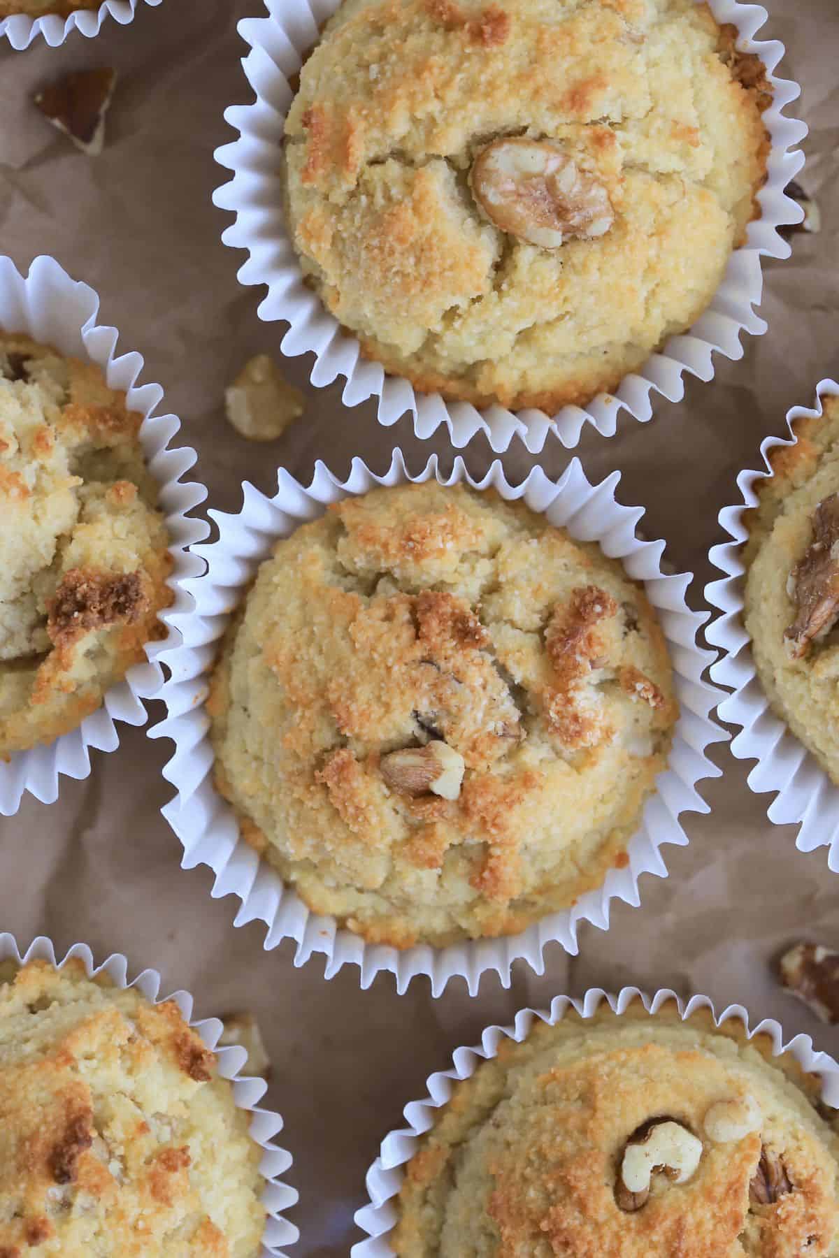 sugar free banana muffins on a brown parchment paper with scattered walnut piecces.