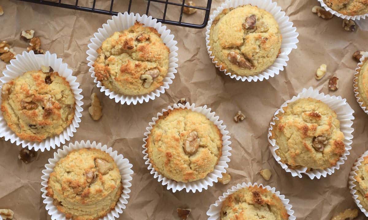 sugar free banana muffins on a brown parchment paper with scattered walnut piecces.