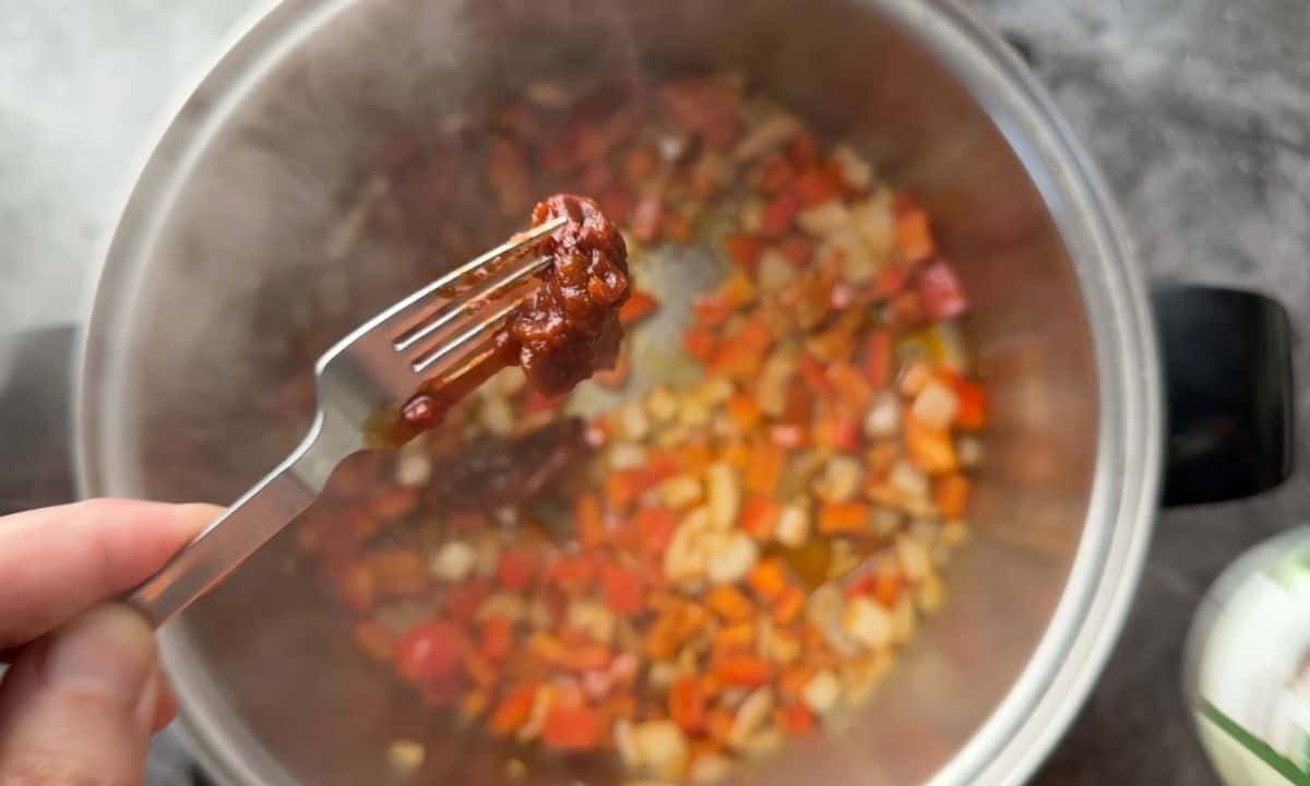 Adding the adobo peppers to the soup pot.