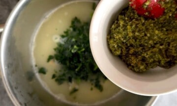 Adding pesto to the soup pot.