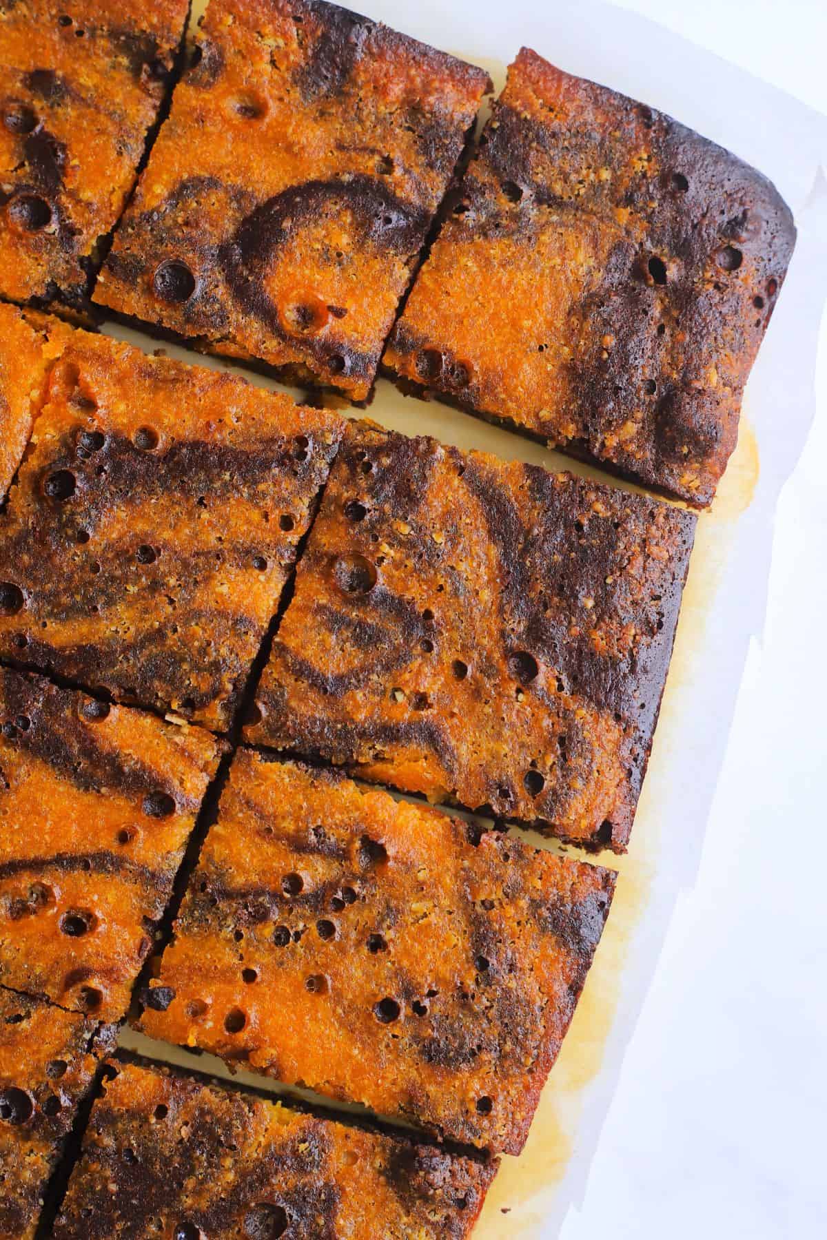 Healthy pumpkin brownie squares on a parchment sheet.