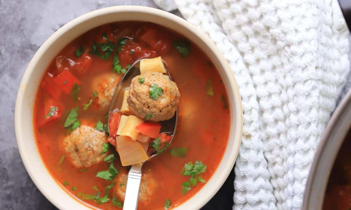 Low Carb Albondigas Mexican Meatball Soup Recipe in a bowl next to a white hand towel.