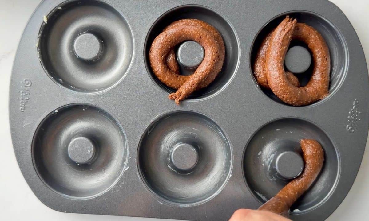 Piping the donut batter into the donut pan.