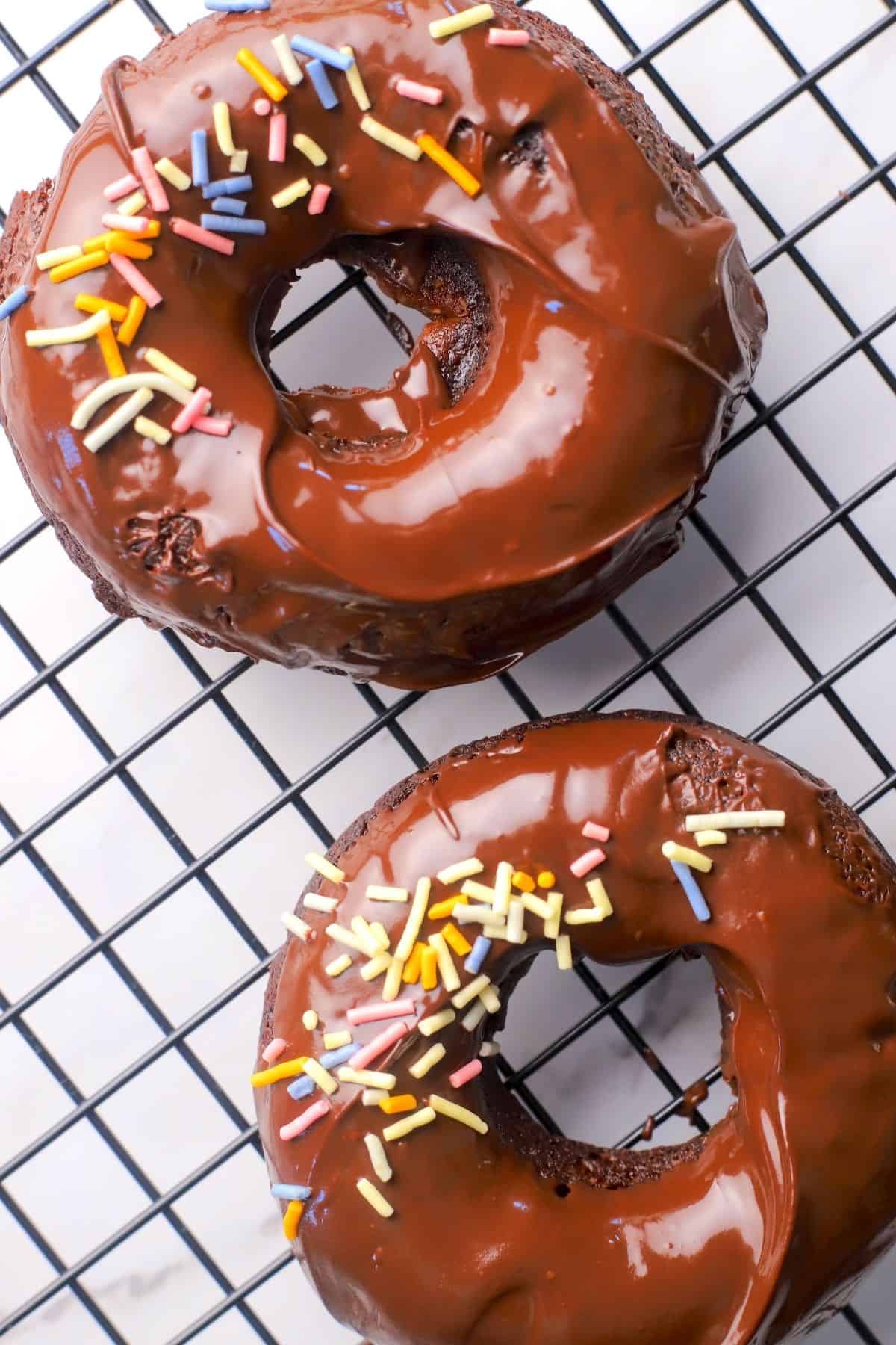 Chocolate sugar free collagen donuts on a wire rack.