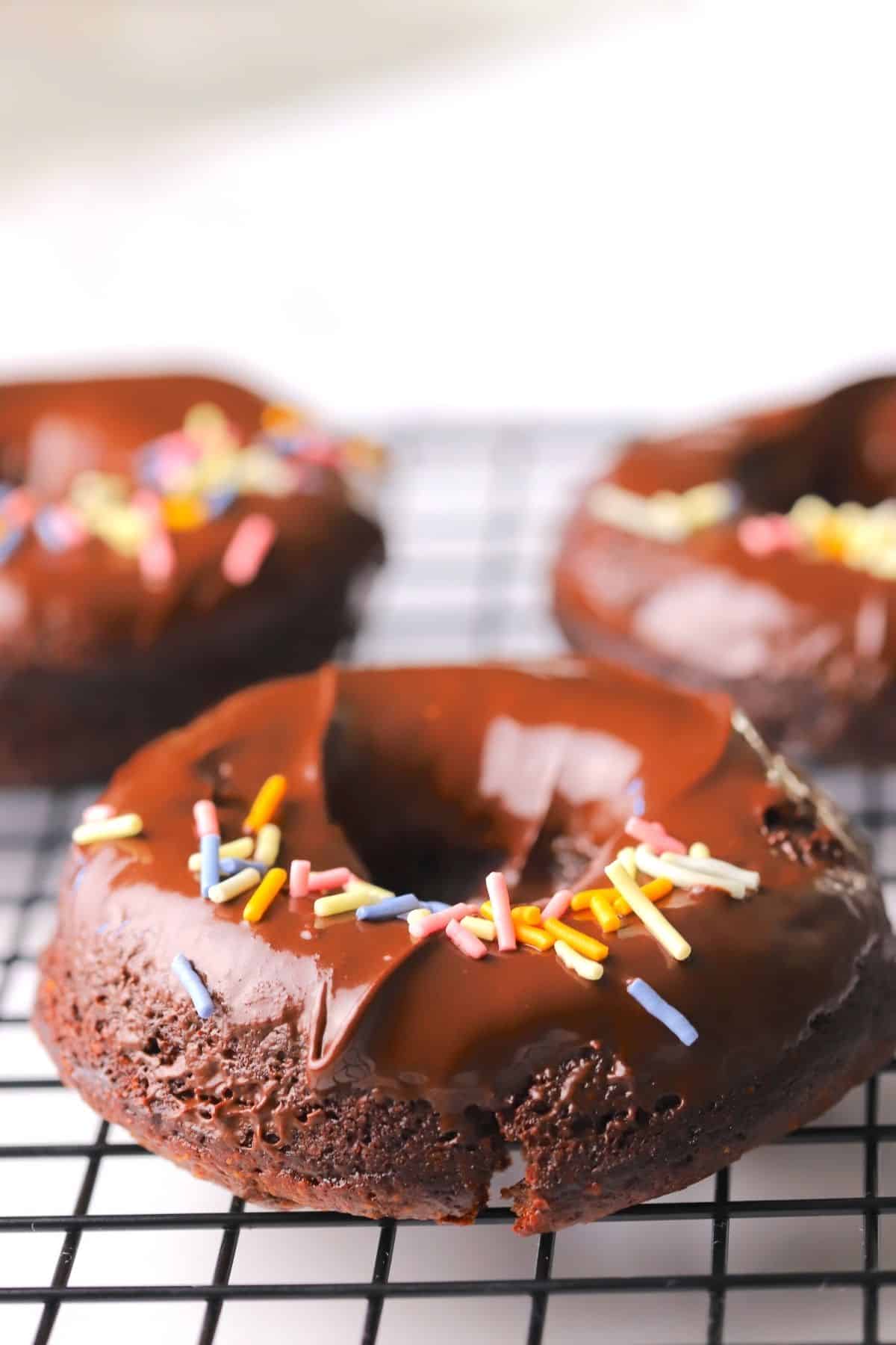 Chocolate sugar free collagen donuts on a wire rack.