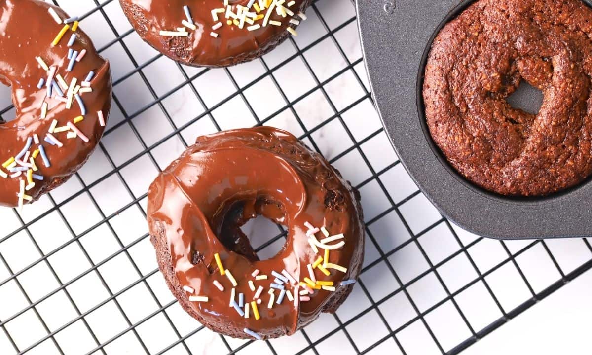 Collagen donuts on a wire rack with a chocolate frosting and sprinkles.