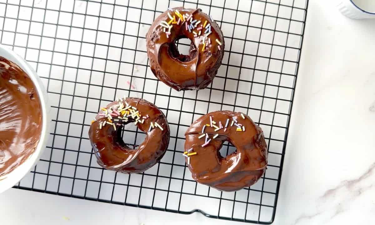 Collagen donuts on a wire rack with a chocolate dip and sprinkles.