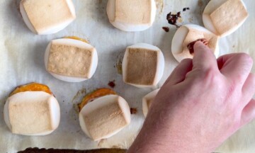 Inserting a pecan on top of the marshmallow covered sweet potatoes.