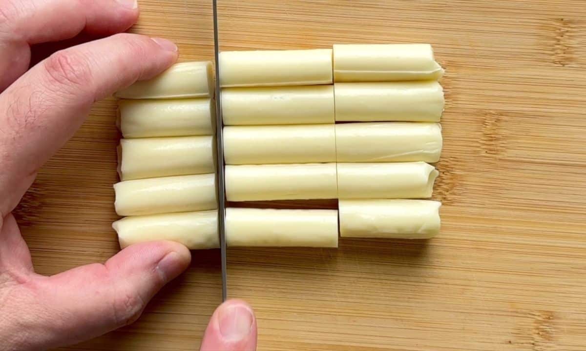 Cutting the mozzarella cheese strings on a cutting board.