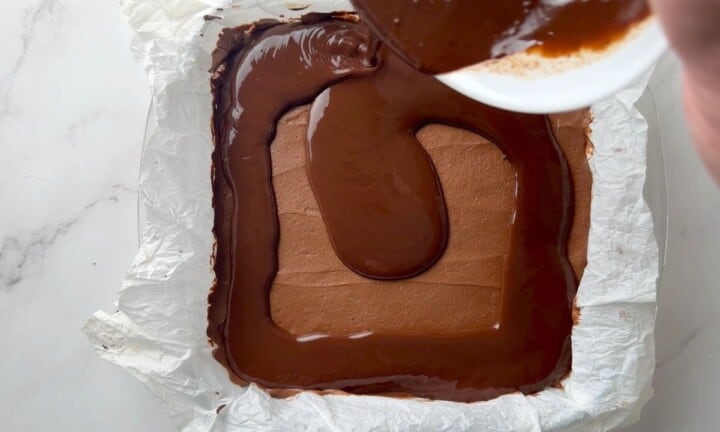 Pouring the chocolate ganache over the cheesecake filling.