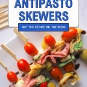 Low carb antipasto skewers on a white platter drizzled with balsamic vinegar.
