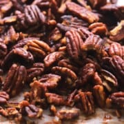 Low carb candied pecans on a parchment lined baking sheet.
