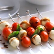Low carb caprese bites on a platter drizzled with balsamic vinegar.