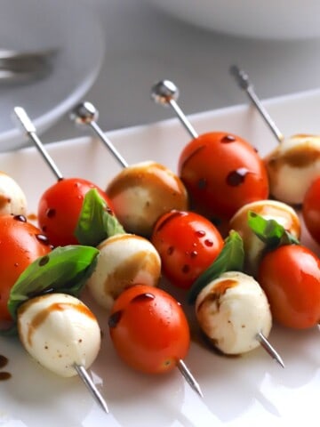 Low carb caprese bites on a platter drizzled with balsamic vinegar.