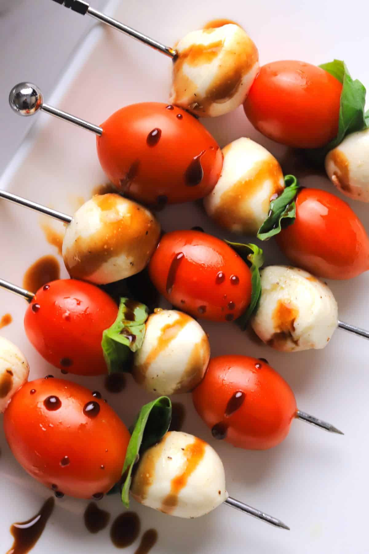 Low carb caprese bites on a platter drizzled with balsamic vinegar.