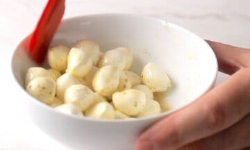 Mixing the bocconcini in the marinade mixture.