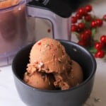 The sugar free peppermint ice cream in a bowl next to the ninja creami container and some missle toe.