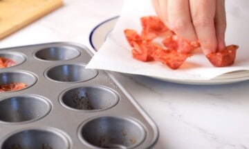 Placing the baked salami cups onto a plate lined with paper towel.