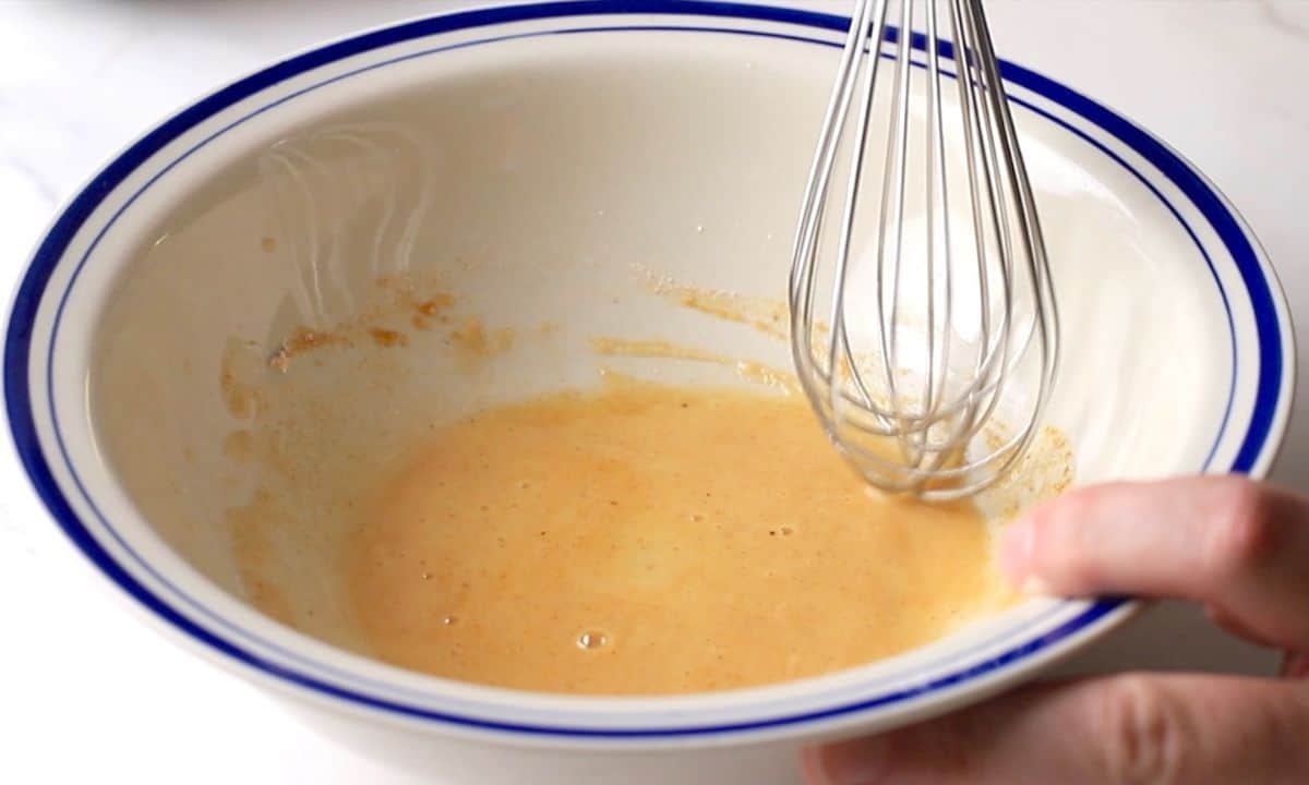 Whisking the glaze mixture in a white bowl.