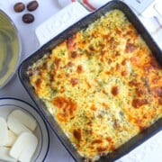 Baked low carb protein lasagne next to a plate of halloumi, bechamel sauce and nutmeg pods.