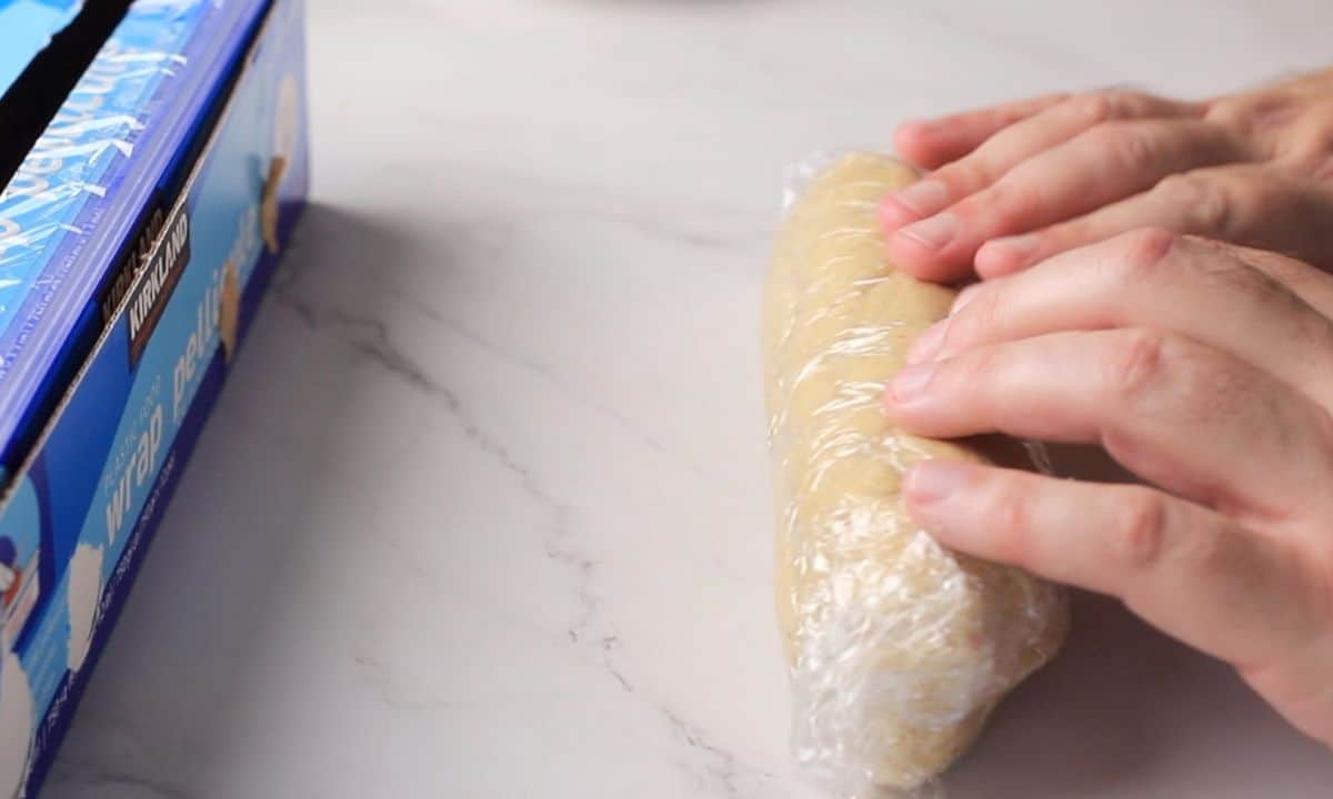 Rolling the cookie dough in plastic wrap.