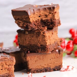 Stacked squares of the sugar free peppermint mocha cheesecake bars with a missle toe in the background.