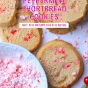 Sugar free peppermint shortbread cookies topped with crushed candy canes on a white plate next to a bowl of crushed candy canes.