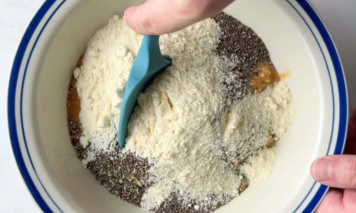 Mixing the ingredients in a large bowl with a blue rubber spatula.