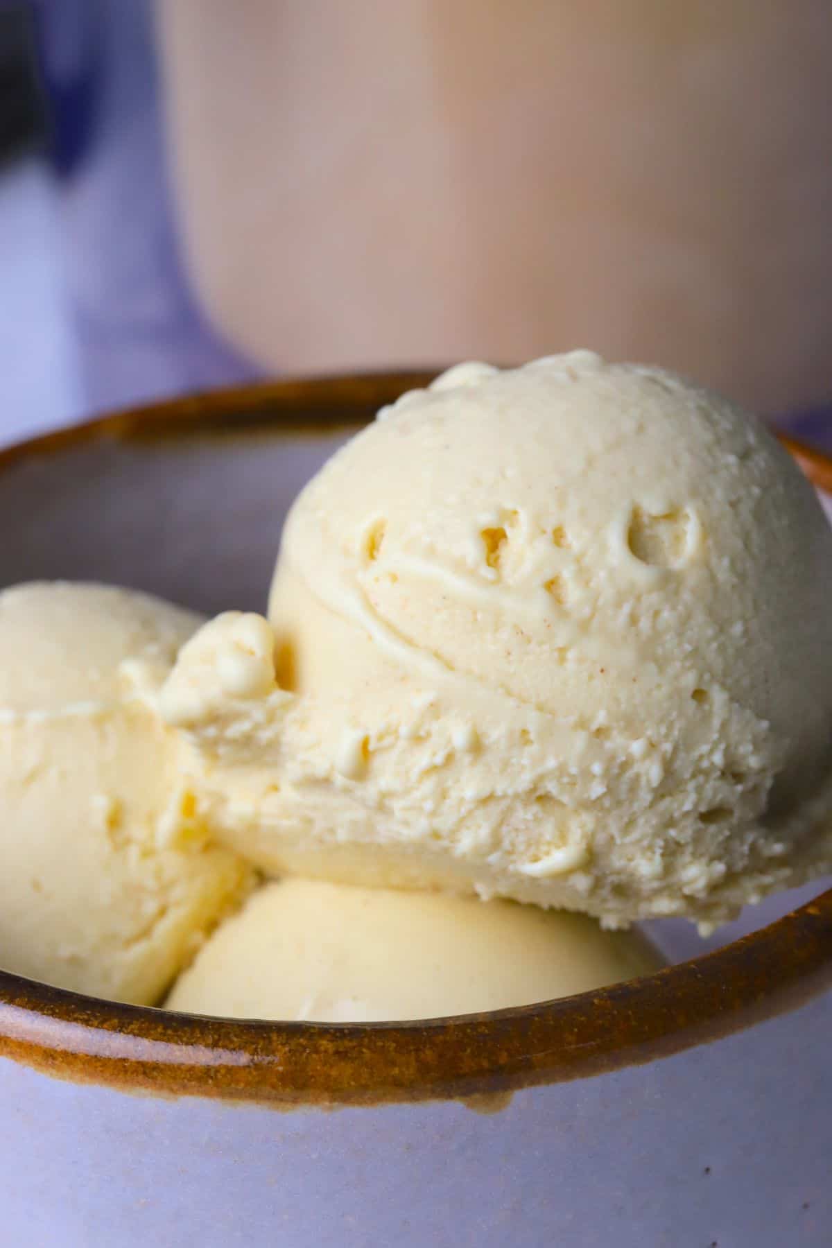 Sugar free eggnog ice cream in a bowl next to the ninja creami container.