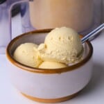 Sugar free eggnog ice cream in a bowl next to the ninja creami container.