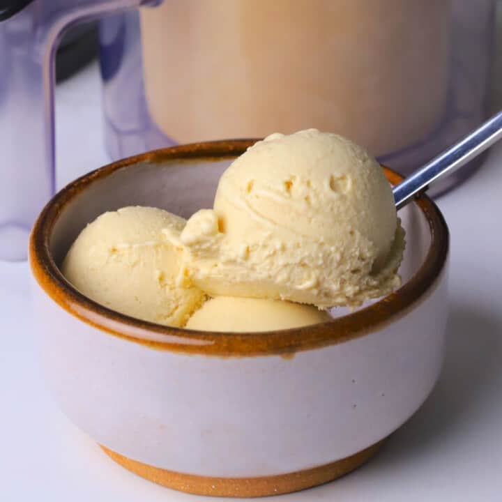 Sugar free eggnog ice cream in a bowl next to the ninja creami container.
